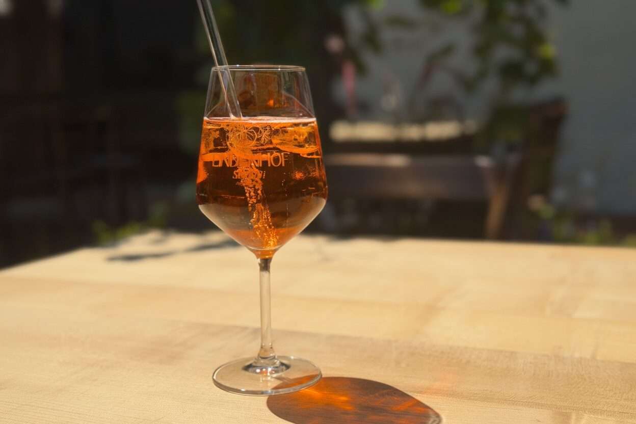 Ein Glas Aperol Spritz auf einem Tisch im Außenbereich der Lindenhof Straußi in Müllheim.